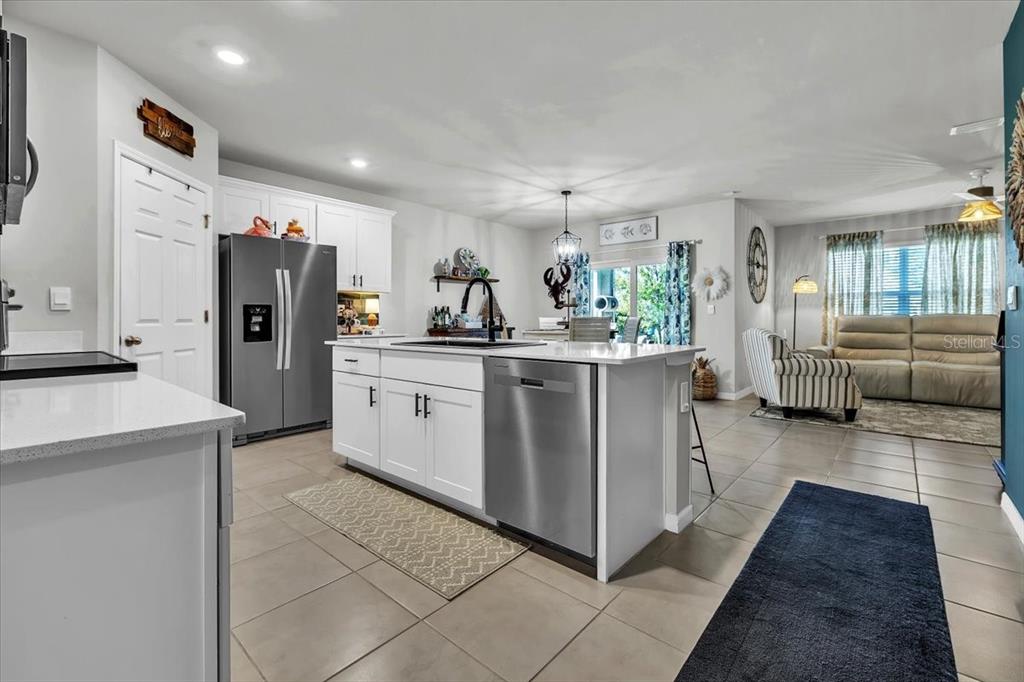 A kitchen with white cabinets and a stainless steel island opens into a living area — 25157 ALCAZAR, PUNTA GORDA, FL