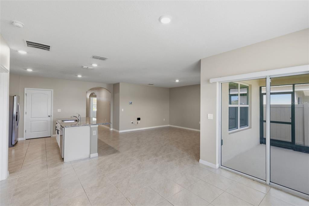 An open-concept living area with tile floors, a kitchen island, and sliding glass patio doors — 5725 SUNBONNET WAY, ST CLOUD, FL