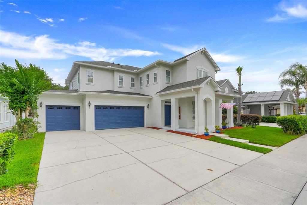 A two-story suburban house with a three-car garage, light siding, and a concrete driveway — 7242 LONDALE BOULEVARD, WINDERMERE, FL