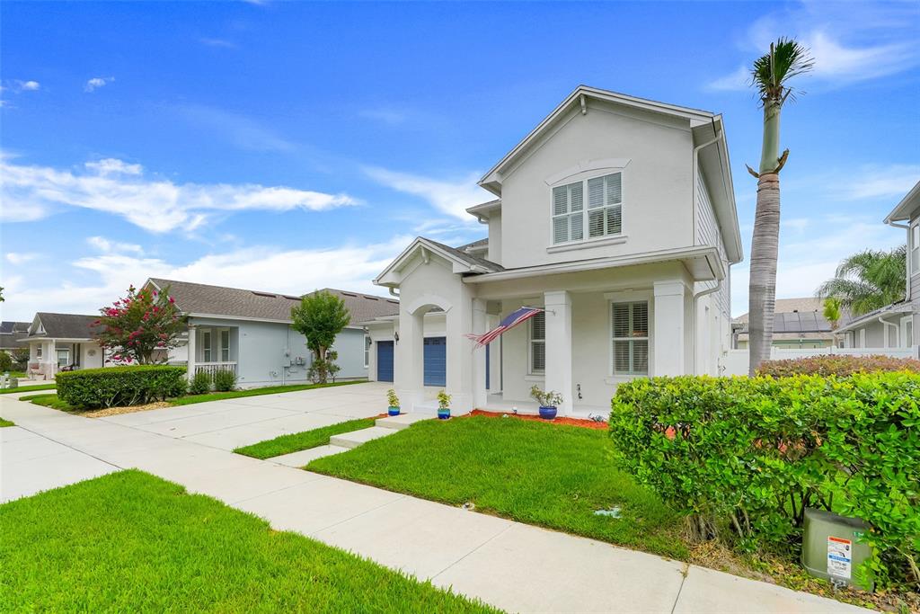 A two-story white house with a front porch, blue garage doors, and a manicured lawn — 7242 LONDALE BOULEVARD, WINDERMERE, FL