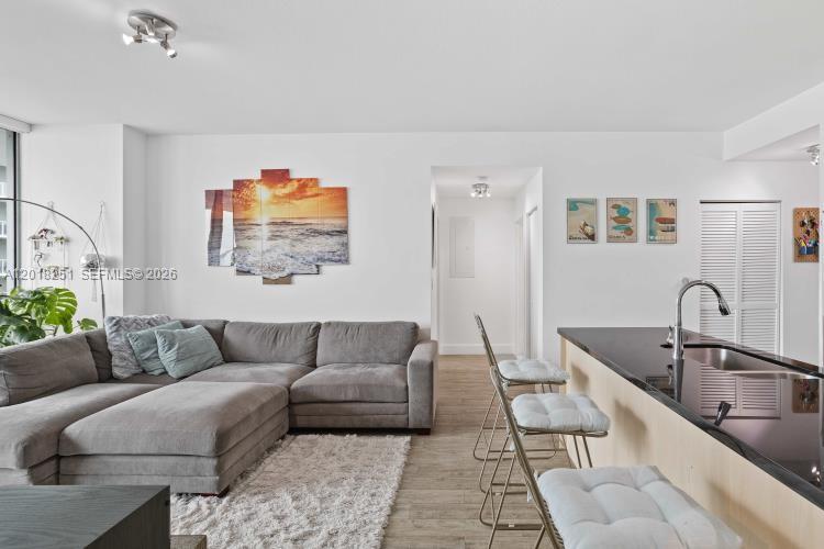 A living room with a gray sectional sofa and an adjacent kitchen island with stools — 79 SW 12th St, Miami FL 33130, MIAMI, FL
