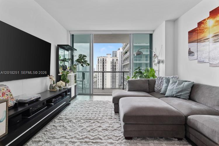 A living room features a large grey sectional sofa, a black media console, and a balcony — 79 SW 12th St, Miami FL 33130, MIAMI, FL