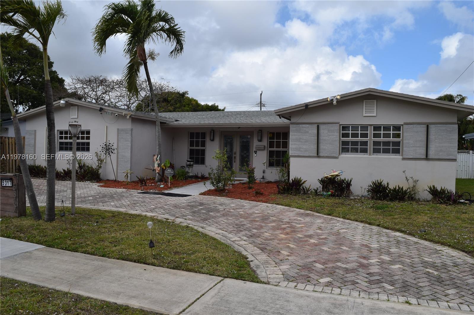 A single-story house with a brick driveway, palm trees, and a gray exterior — 5317 Van Buren St, Hollywood FL 33021, HOLLYWOOD, FL