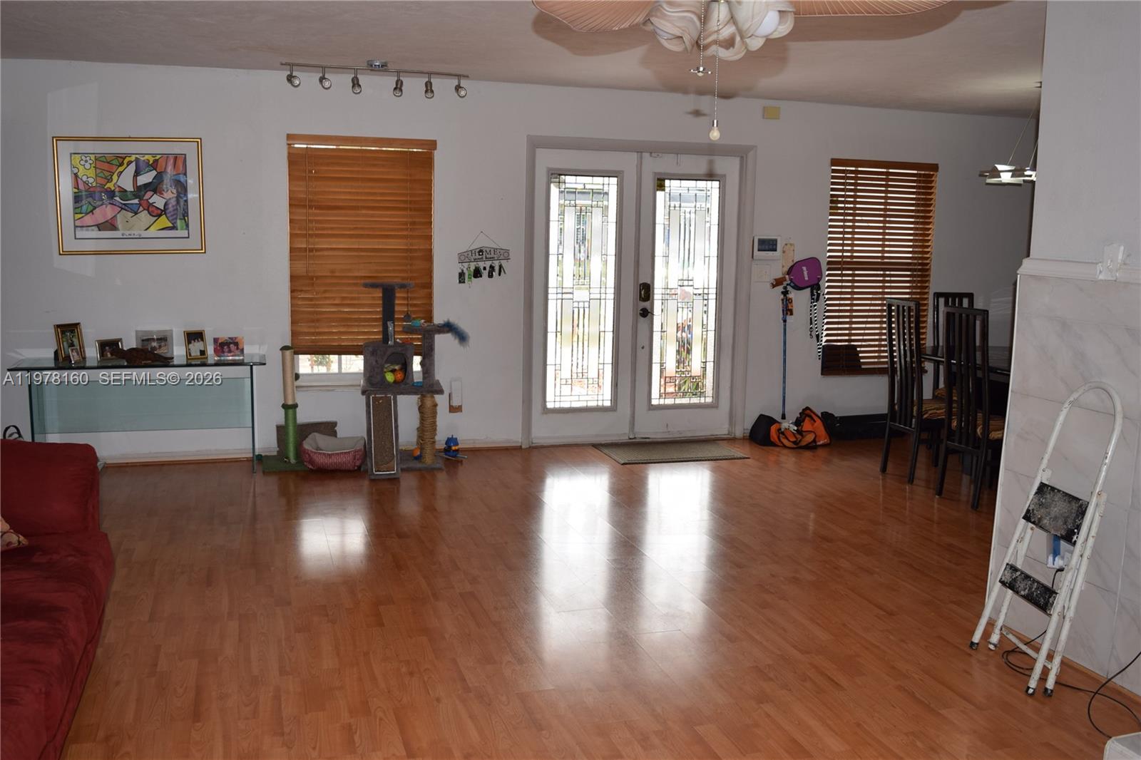 A living room features wood flooring, a glass console table, a cat tree, and double doors — 5317 Van Buren St, Hollywood FL 33021, HOLLYWOOD, FL