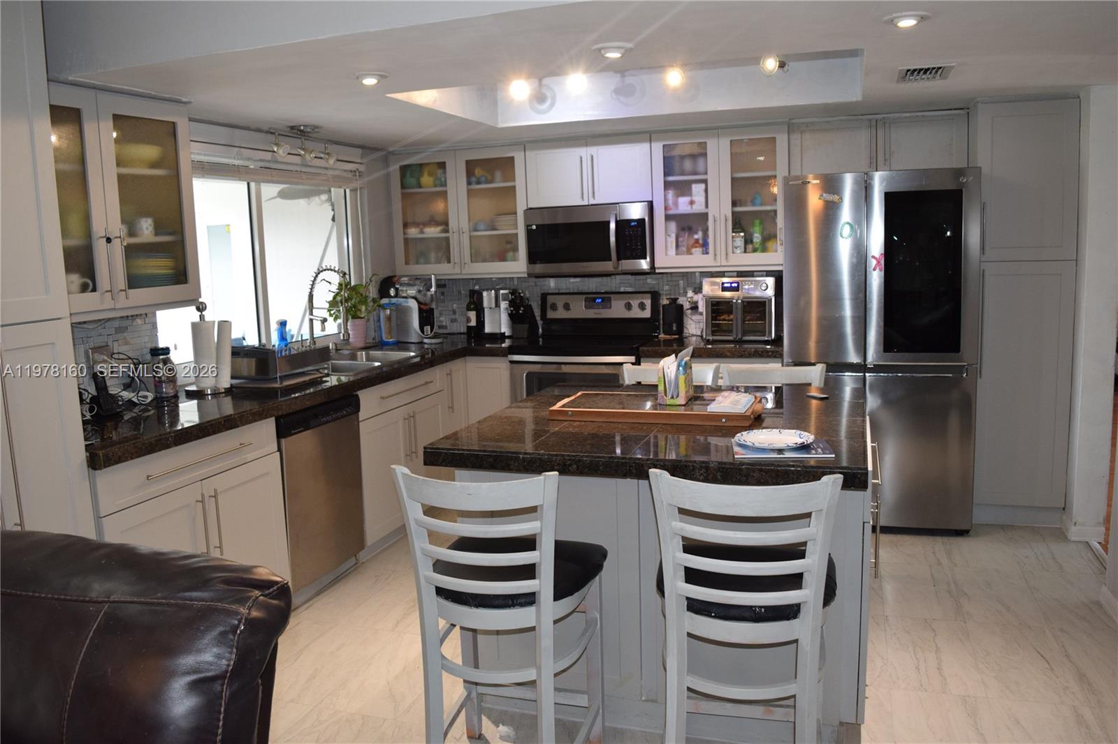 A kitchen features light-colored cabinets, dark granite countertops, stainless steel appliances, and a central island — 5317 Van Buren St, Hollywood FL 33021, HOLLYWOOD, FL