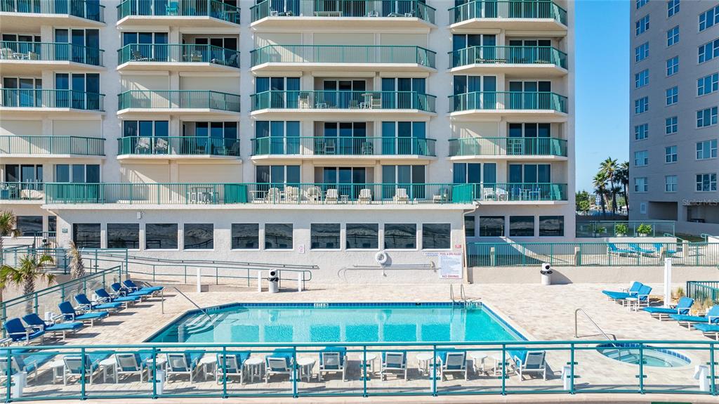 An outdoor swimming pool and spa are situated on a patio in front of a building — 3311 S ATLANTIC AVENUE UNIT 201, DAYTONA BEACH SHORES, FL