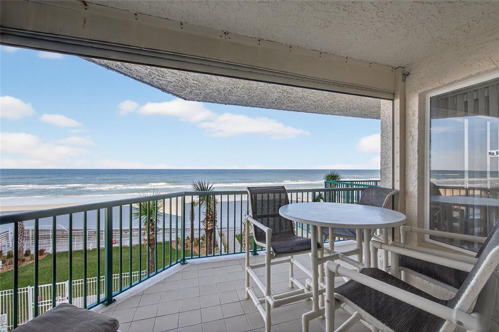A balcony with outdoor furniture overlooks the ocean and a sandy beach — 3311 S ATLANTIC AVENUE UNIT 201, DAYTONA BEACH SHORES, FL