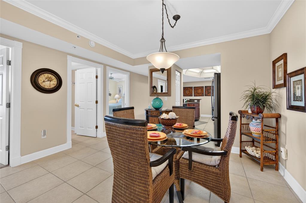 A dining area features a glass-topped table with wicker chairs and tile flooring — 3311 S ATLANTIC AVENUE UNIT 201, DAYTONA BEACH SHORES, FL