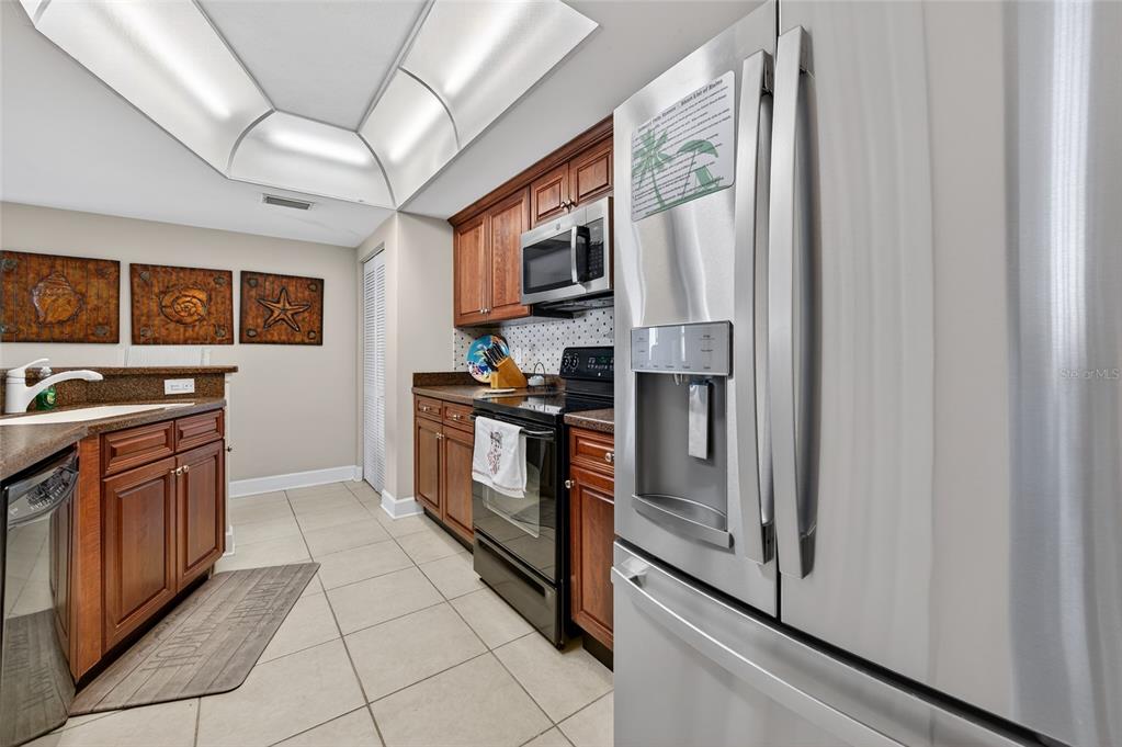 A kitchen features wood cabinets, stainless steel appliances, tile flooring, and a recessed ceiling light — 3311 S ATLANTIC AVENUE UNIT 201, DAYTONA BEACH SHORES, FL
