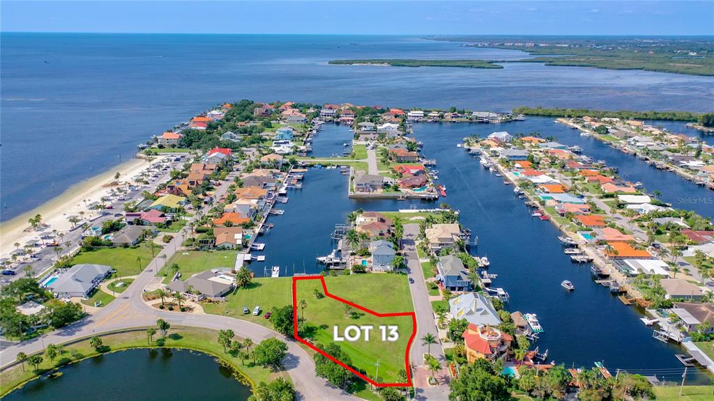 An aerial view shows a vacant waterfront lot highlighted in red within a residential neighborhood — Lot 13 CAPTAINS COURT, NEW PORT RICHEY, FL