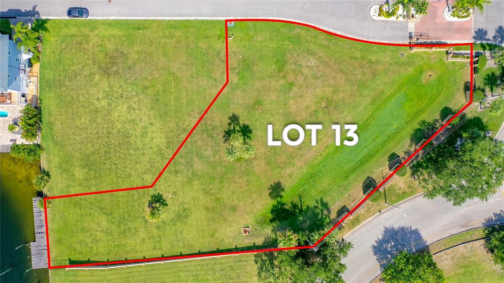 An aerial view shows a vacant, irregularly shaped residential lot outlined in red — Lot 13 CAPTAINS COURT, NEW PORT RICHEY, FL
