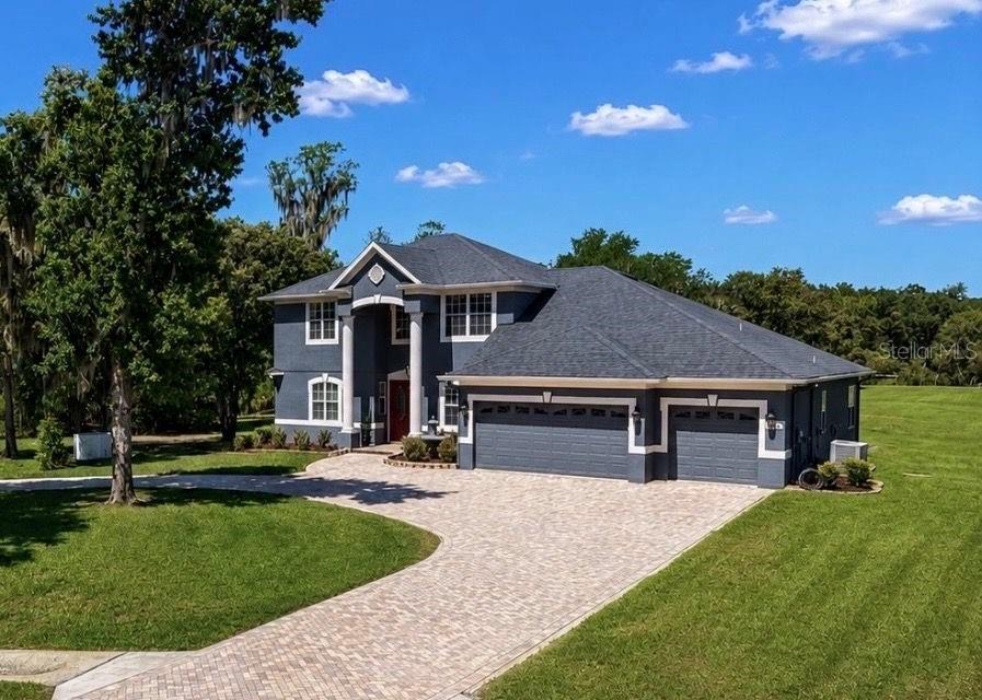 A two-story house with a dark gray exterior, a three-car garage, and a paved driveway — 10619 LITHIA ESTATES DRIVE, LITHIA, FL