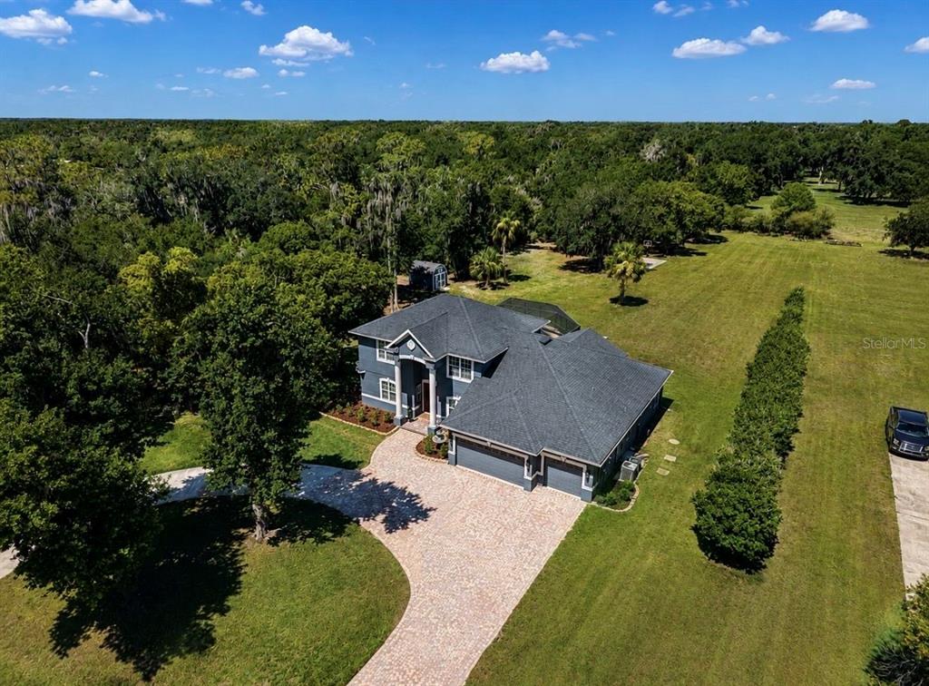 An aerial view shows a two-story house with a gray roof and a paved driveway — 10619 LITHIA ESTATES DRIVE, LITHIA, FL