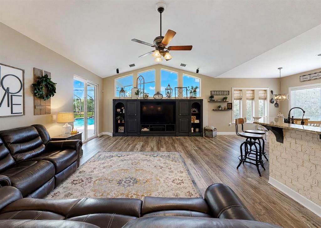 A living room with wood-look flooring, a dark built-in entertainment center, and a ceiling fan — 10619 LITHIA ESTATES DRIVE, LITHIA, FL