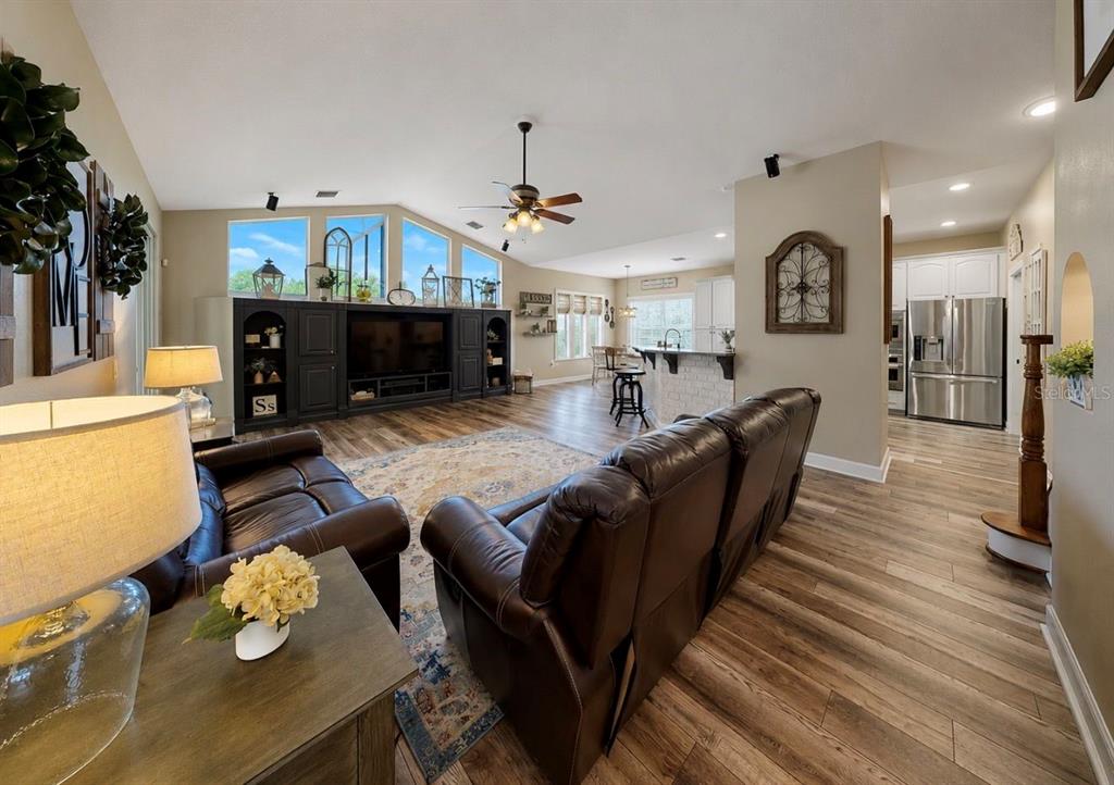 A living room with dark leather furniture, a large media center, and wood-look flooring — 10619 LITHIA ESTATES DRIVE, LITHIA, FL