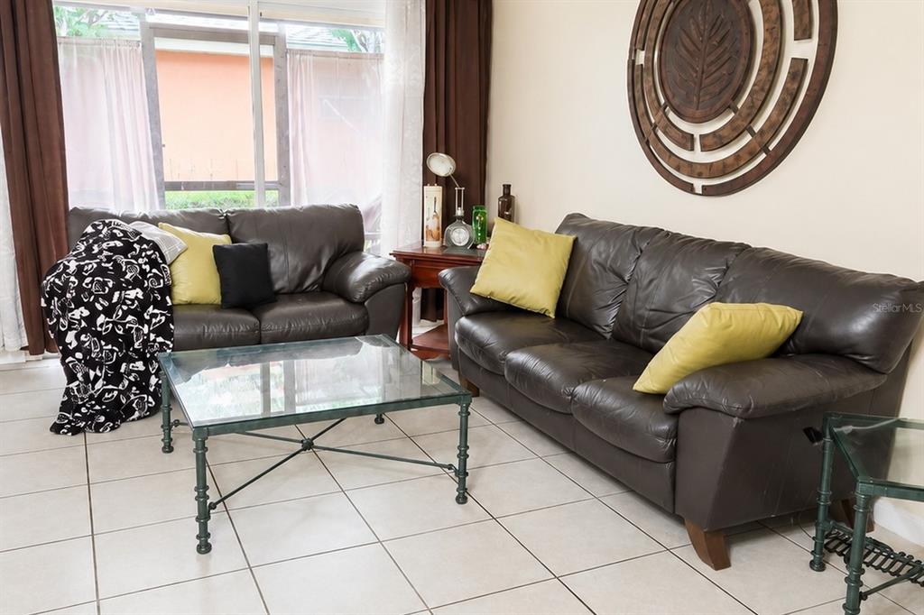 A living room features two dark leather sofas, a glass coffee table, and tile flooring — 4756 TANGERINE AVENUE UNIT 4756, WINTER PARK, FL