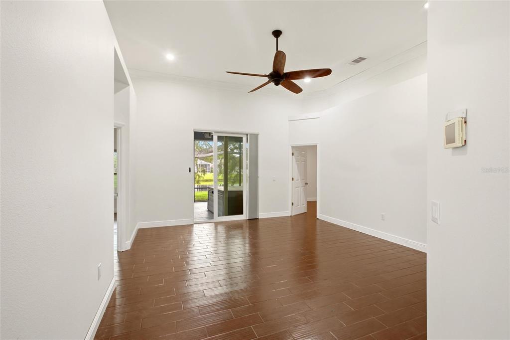 A living room with wood-look tile flooring, a ceiling fan, and sliding glass doors — 12347 HOLLYBUSH TERRACE, BRADENTON, FL