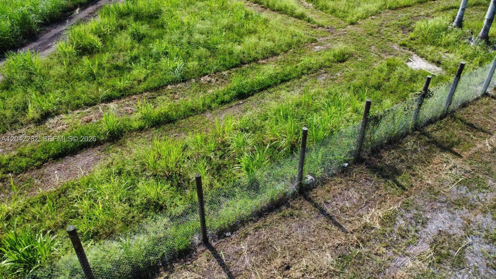 An aerial view shows a grassy field enclosed by a wire mesh fence — 168 St, Miami FL 33187, MIAMI, FL