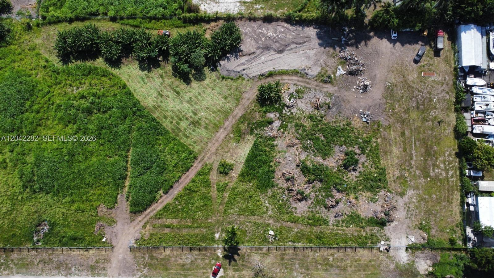 An aerial view shows a large, partially cleared vacant lot with dirt paths and vegetation — 168 St, Miami FL 33187, MIAMI, FL