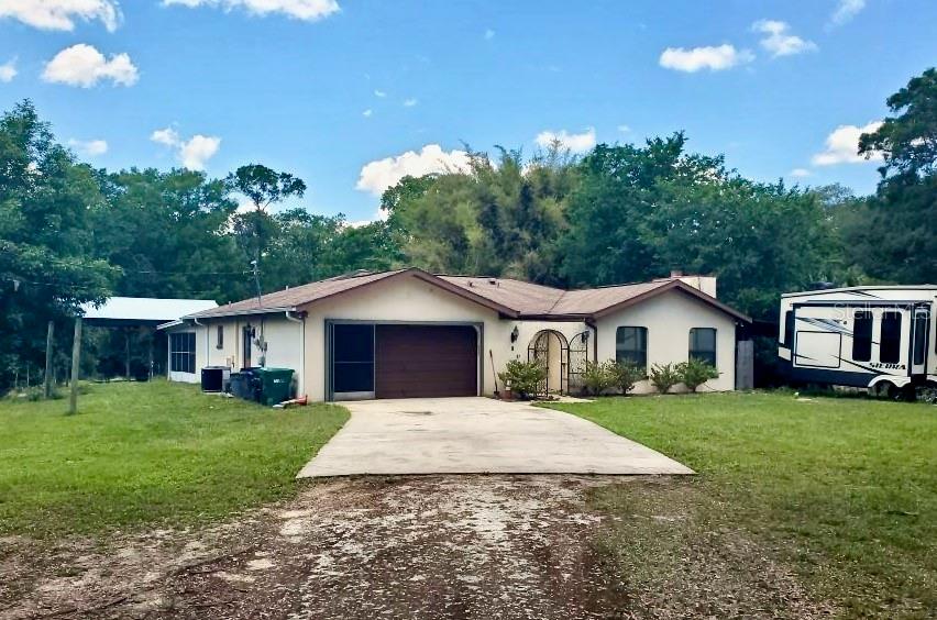 A single-story house with a concrete driveway, a garage, and a parked RV nearby — 490 S MINSTREL AVENUE, INVERNESS, FL