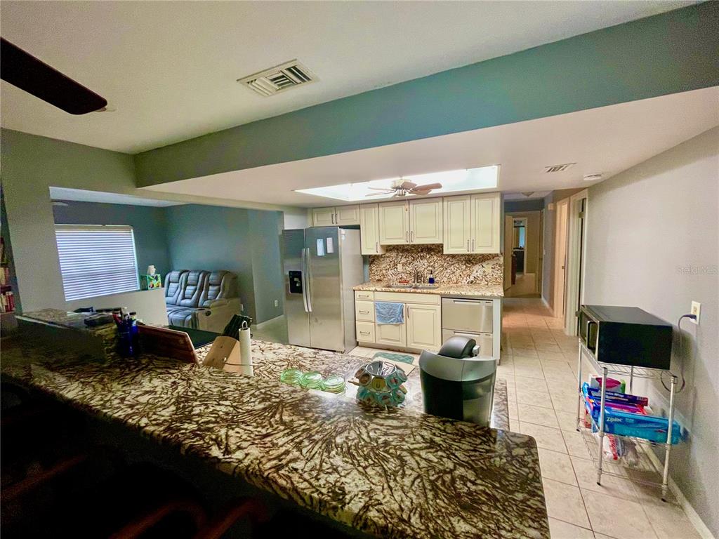 A kitchen features granite countertops, white cabinetry, stainless steel appliances, and a breakfast bar — 490 S MINSTREL AVENUE, INVERNESS, FL