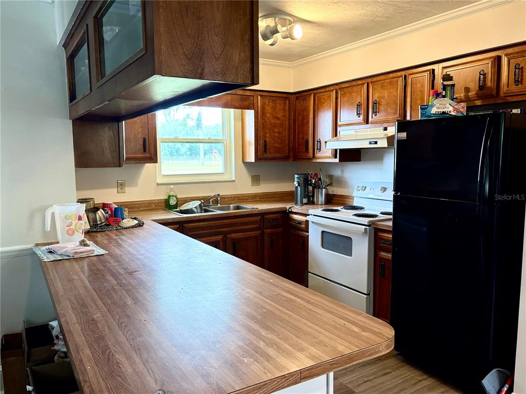 A kitchen features wood cabinets, laminate countertops, a white stove, and a black refrigerator — 507 GOVERNOR AVENUE NE, BRANFORD, FL