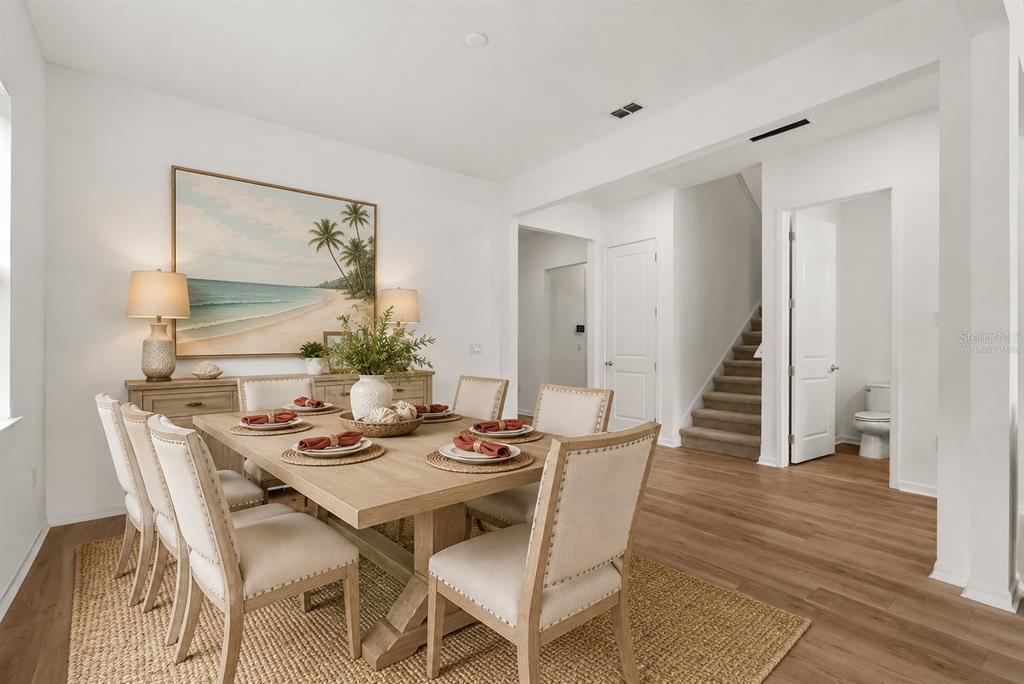 A dining room features a wooden table, upholstered chairs, a beach-themed painting, and hardwood floors — 12105 ORCHID ASH STREET, RIVERVIEW, FL
