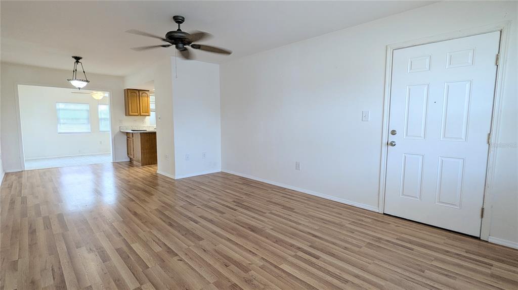 A living room with wood-look flooring, a ceiling fan, and a white front door — 4158 TAMIAMI TRAIL UNIT U3, PORT CHARLOTTE, FL