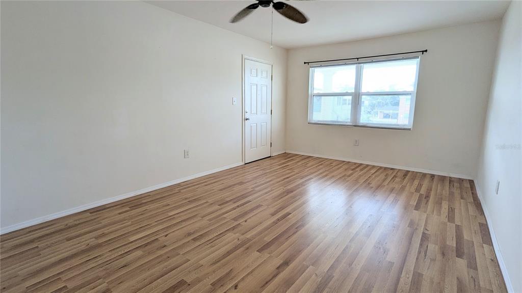 An empty room features light-colored walls, wood-look flooring, a ceiling fan, and a window — 4158 TAMIAMI TRAIL UNIT U3, PORT CHARLOTTE, FL