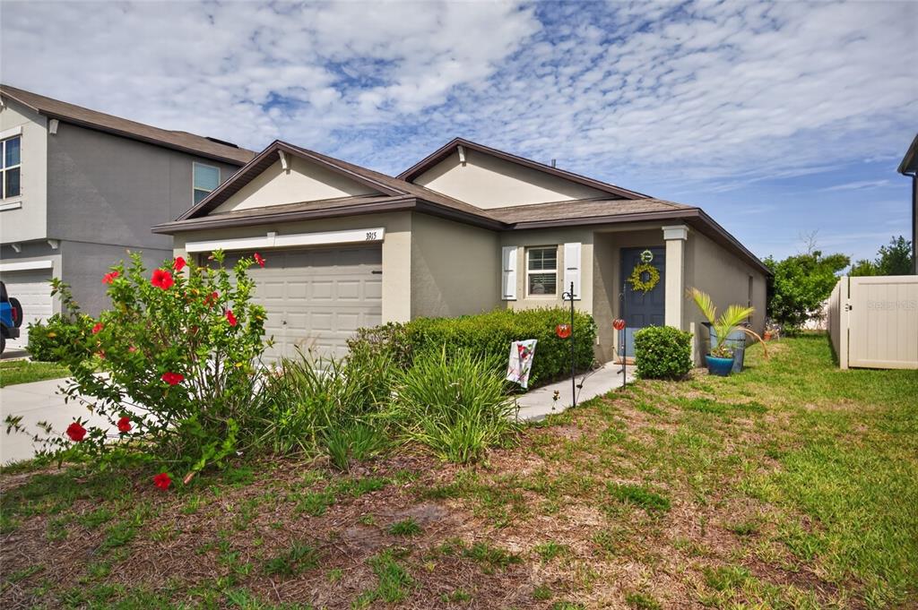 A single-story house with a beige exterior, a two-car garage, and a blue front door — 3915 GAINER SPRINGS AVENUE, NEW PORT RICHEY, FL
