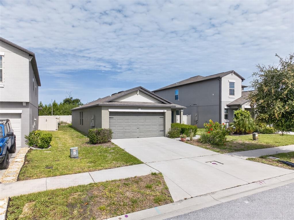 A single-story house with a gray garage and driveway sits between two taller neighboring homes — 3915 GAINER SPRINGS AVENUE, NEW PORT RICHEY, FL