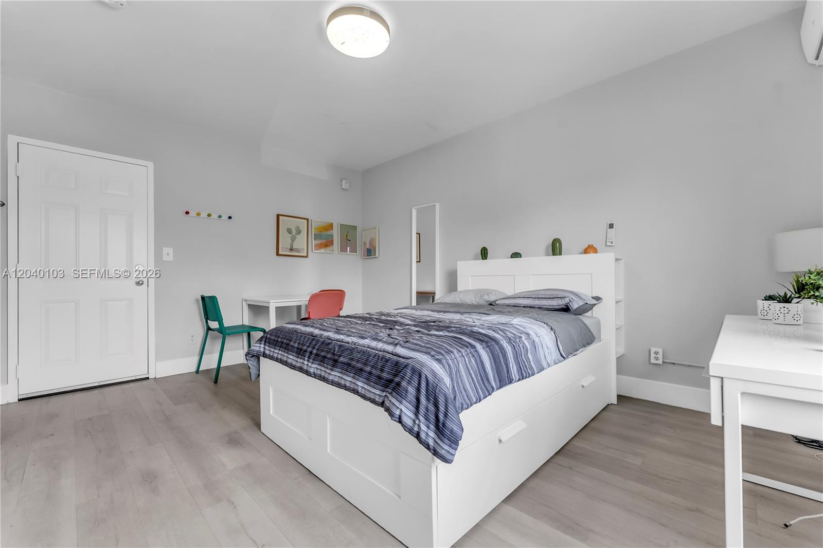 A bedroom features a white bed with storage drawers, light wood flooring, and a small desk — 6647 SW 59th Pl # 208, South Miami FL 33143, SOUTH MIAMI, FL
