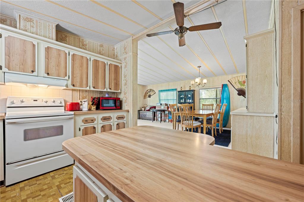 A kitchen with wood-look cabinets and a breakfast bar opens into a dining area — 7373 FALL STREET, BROOKSVILLE, FL