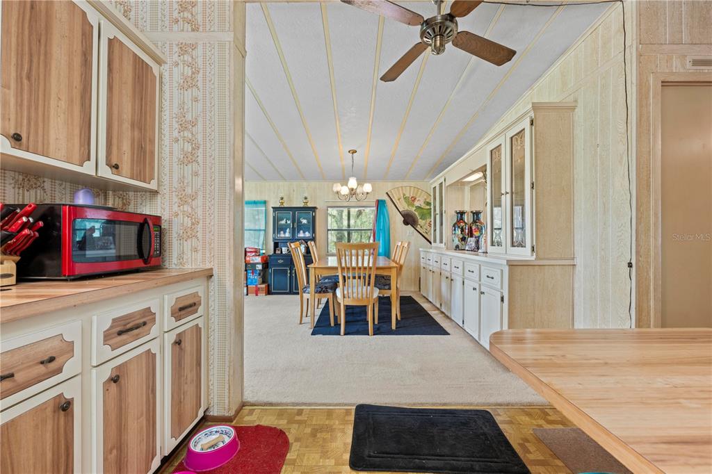 A kitchen with wood-trimmed cabinets looks into a dining area with a table and chairs — 7373 FALL STREET, BROOKSVILLE, FL
