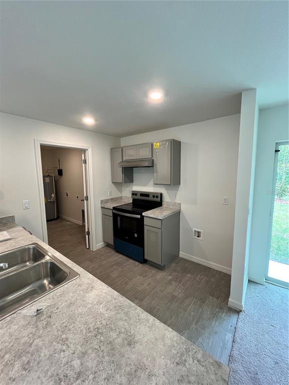 A kitchen features gray cabinets, a black stove, and a laminate countertop — 10300 RUTH AVENUE, HASTINGS, FL