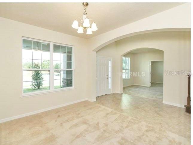 A dining room with tile floors, a chandelier, and an arched entryway to another room — 2103 CANDLENUT CIRCLE, APOPKA, FL