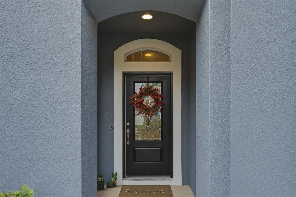 A bright foyer features tile flooring, a central staircase with wooden railings, and arched doorways — 4446 WILDSTAR CIRCLE, WESLEY CHAPEL, FL