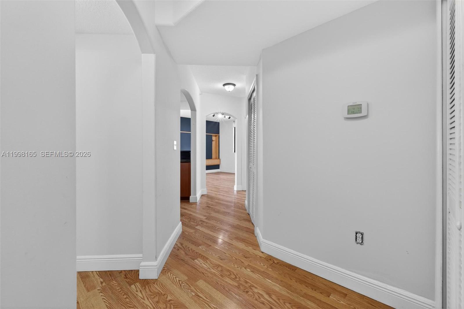 A hallway with light-colored walls, hardwood flooring, and arched doorways leads to another room — 2301 SW 27th Ave # 906, Miami FL 33145, MIAMI, FL