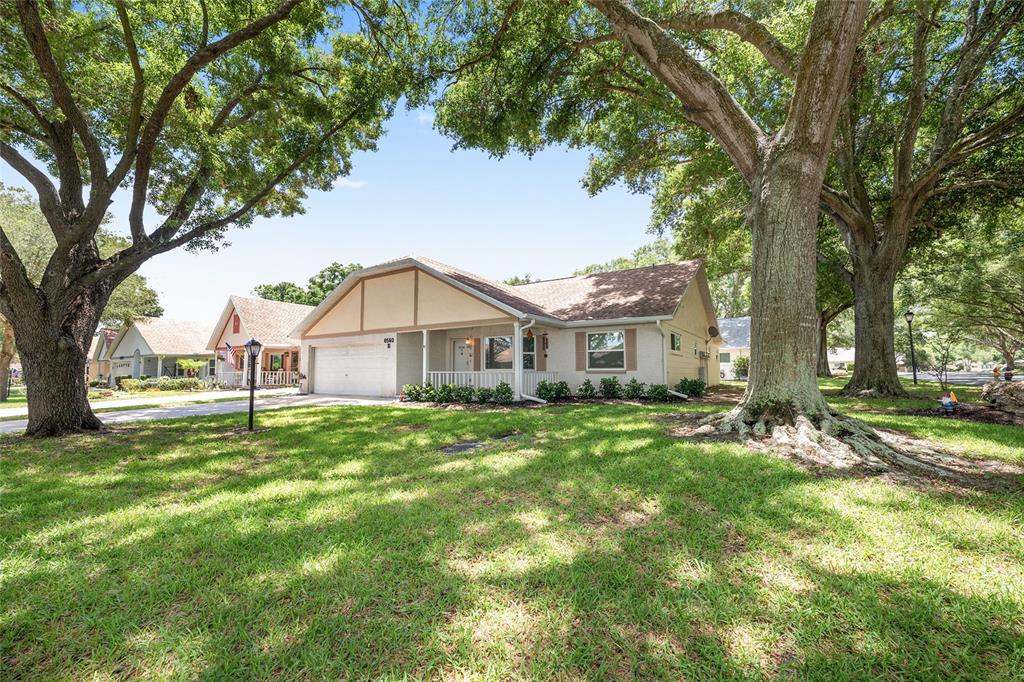 A single-story house with a white garage and porch sits on a grassy, tree-shaded lot — 8560 SW 90TH STREET UNIT E, OCALA, FL