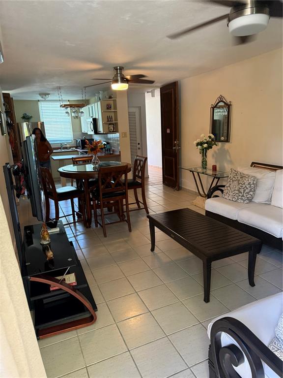 An open-concept living and dining area features tile flooring, ceiling fans, and a kitchen background — COSTA BRAVA EDIF 8 UNIT 102, CEIBA, PR