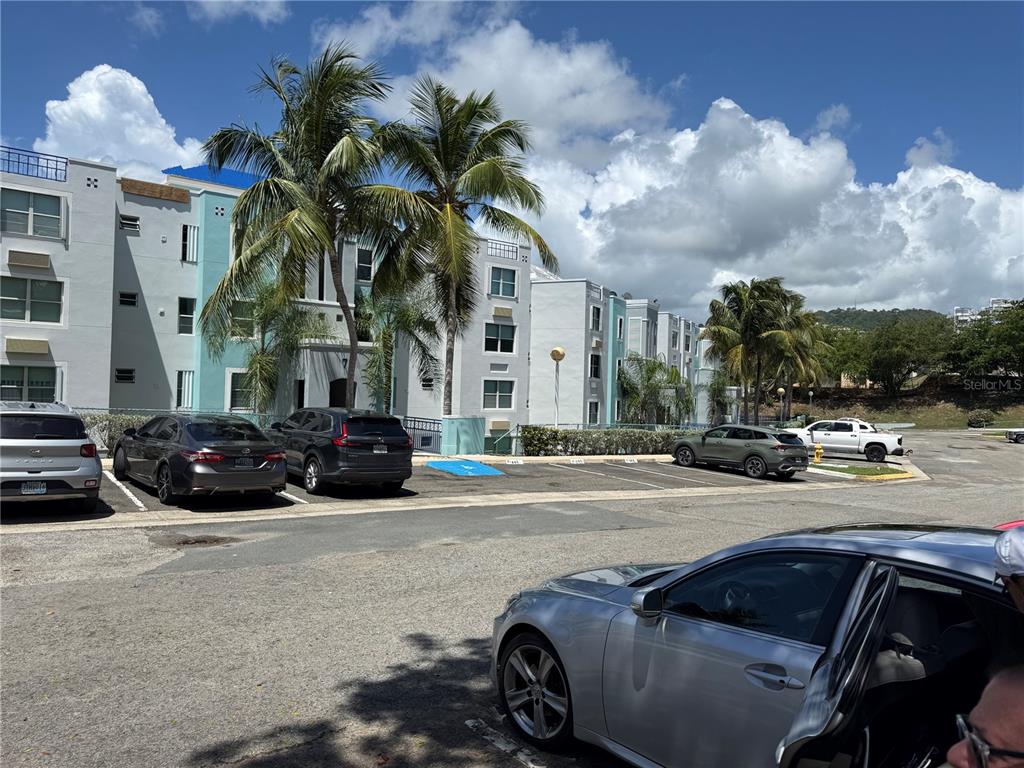 A multi-story apartment complex with palm trees and a parking lot in the foreground — COSTA BRAVA EDIF 8 UNIT 102, CEIBA, PR