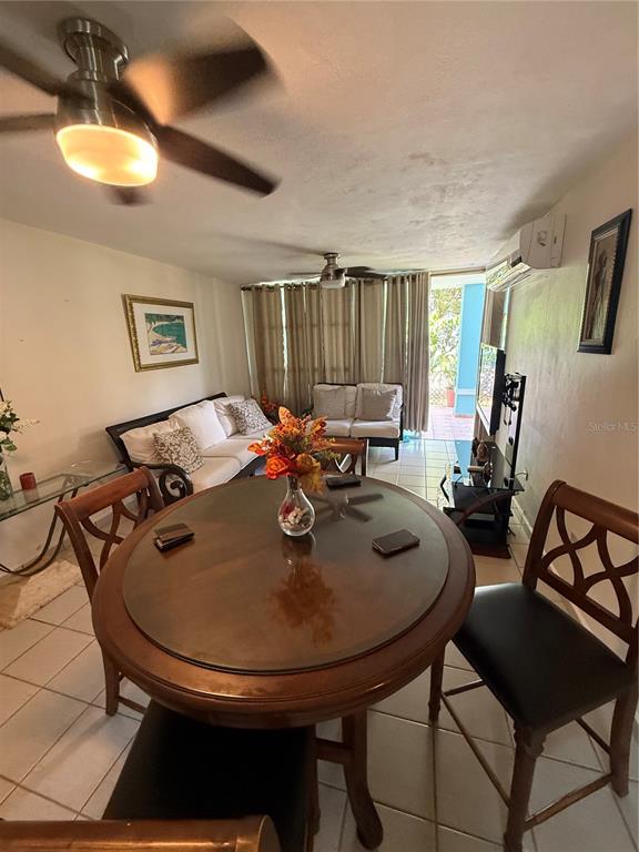 A dining area with a round wooden table and chairs opens into a living room — COSTA BRAVA EDIF 8 UNIT 102, CEIBA, PR