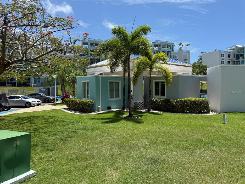 A small, light blue building with palm trees stands on a grassy lawn near parking — COSTA BRAVA EDIF 8 UNIT 102, CEIBA, PR