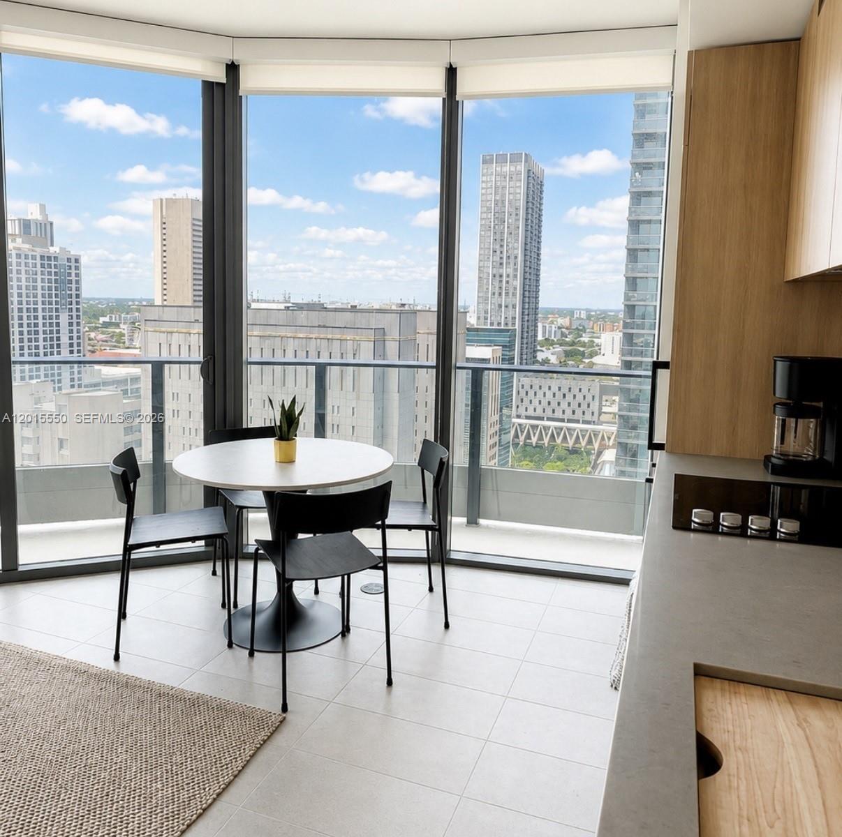 A modern kitchen dining area features a round table, black chairs, and floor-to-ceiling windows — 121 NE 5th St # 2705, Miami FL 33132, MIAMI, FL