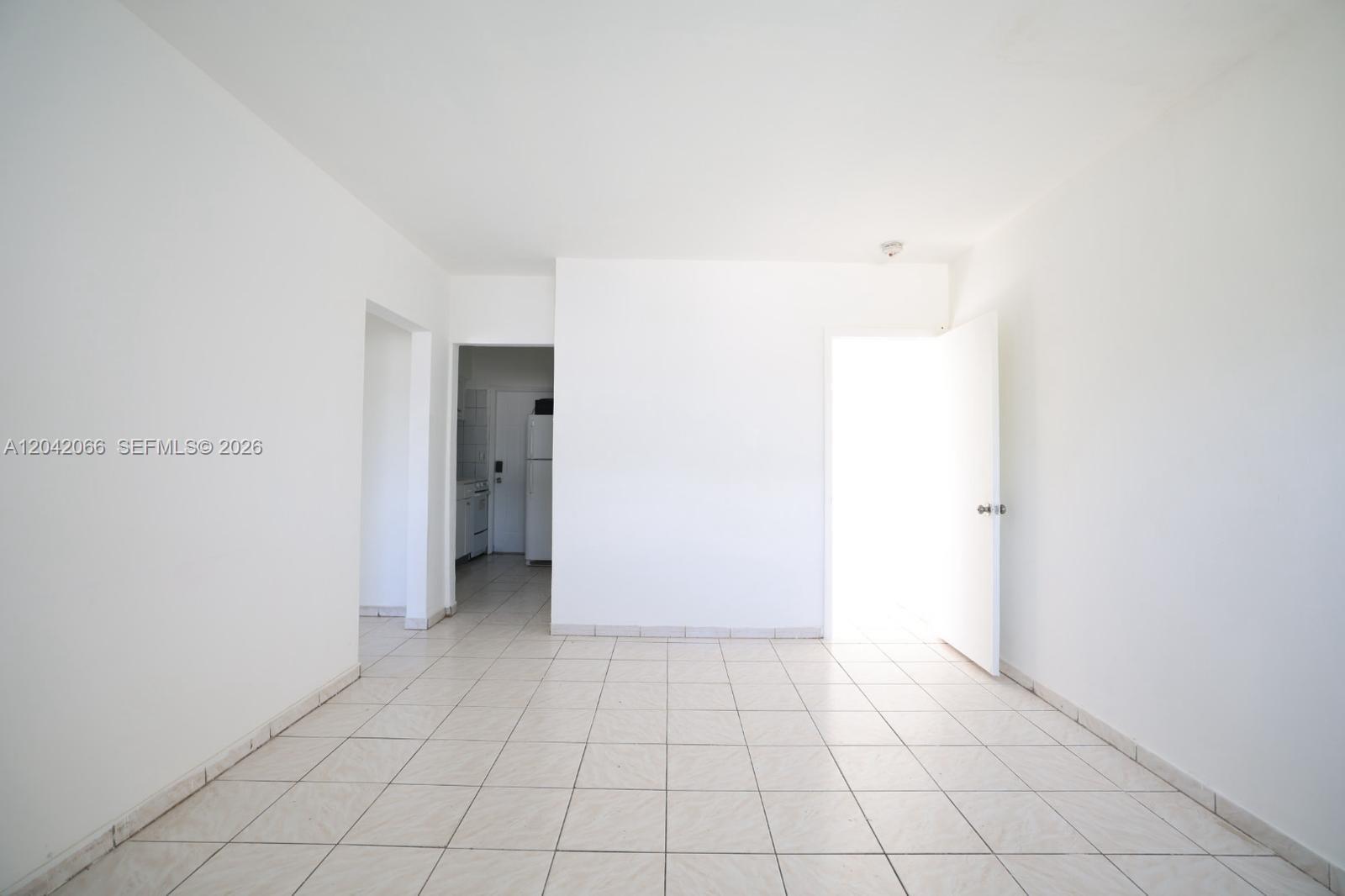 An empty room with white walls and light-colored square floor tiles features two doorways — 770 83rd St # 3, Miami Beach FL 33141, MIAMI BEACH, FL