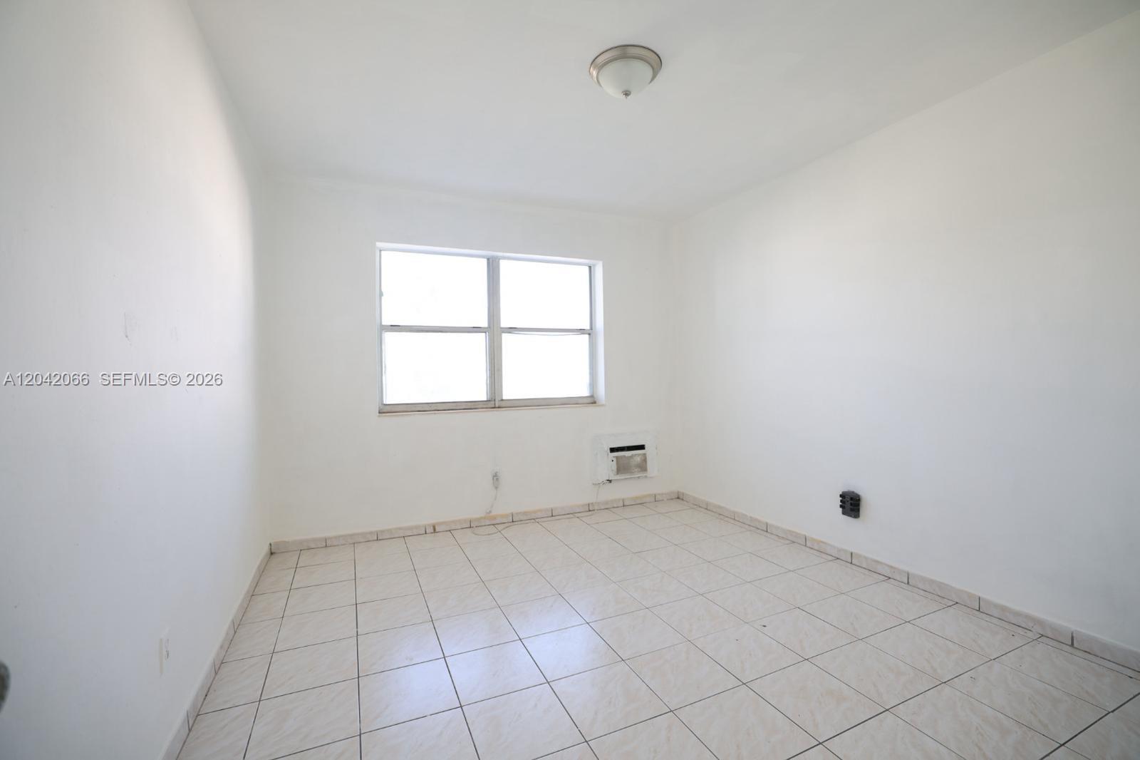An empty room features white walls, light-colored tile flooring, a window, and a ceiling light — 770 83rd St # 3, Miami Beach FL 33141, MIAMI BEACH, FL