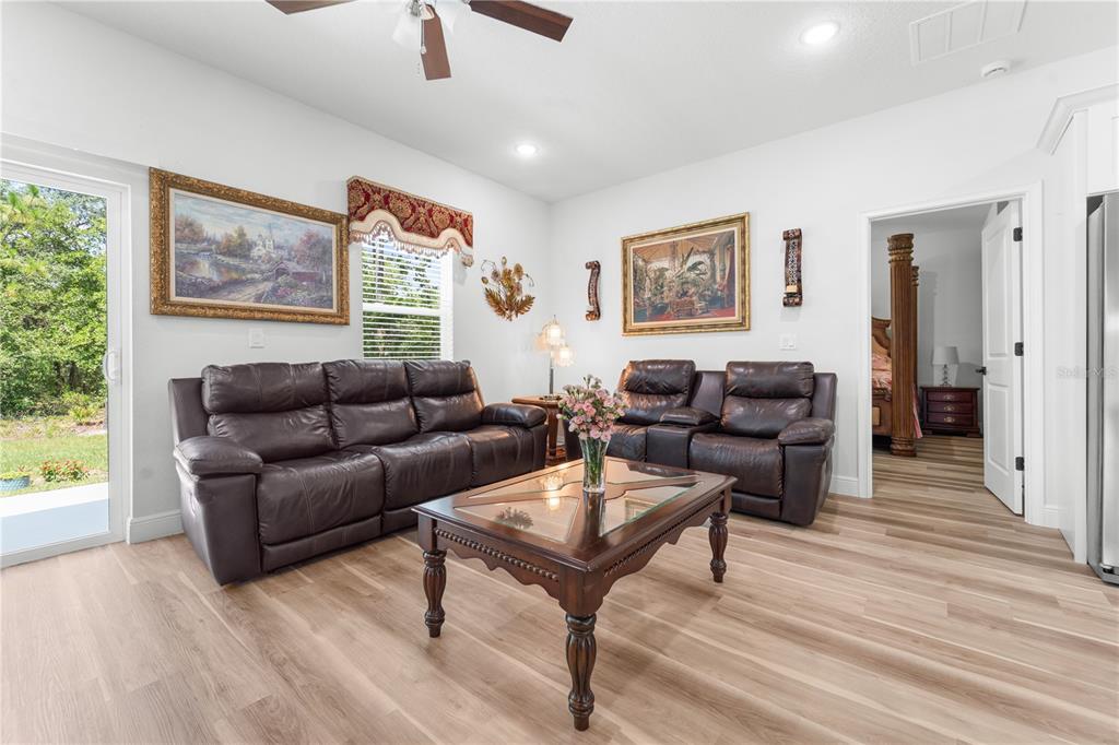 A living room features two dark leather sofas, a glass-top coffee table, and wood-look flooring — 768 MARION OAKS MANOR, OCALA, FL