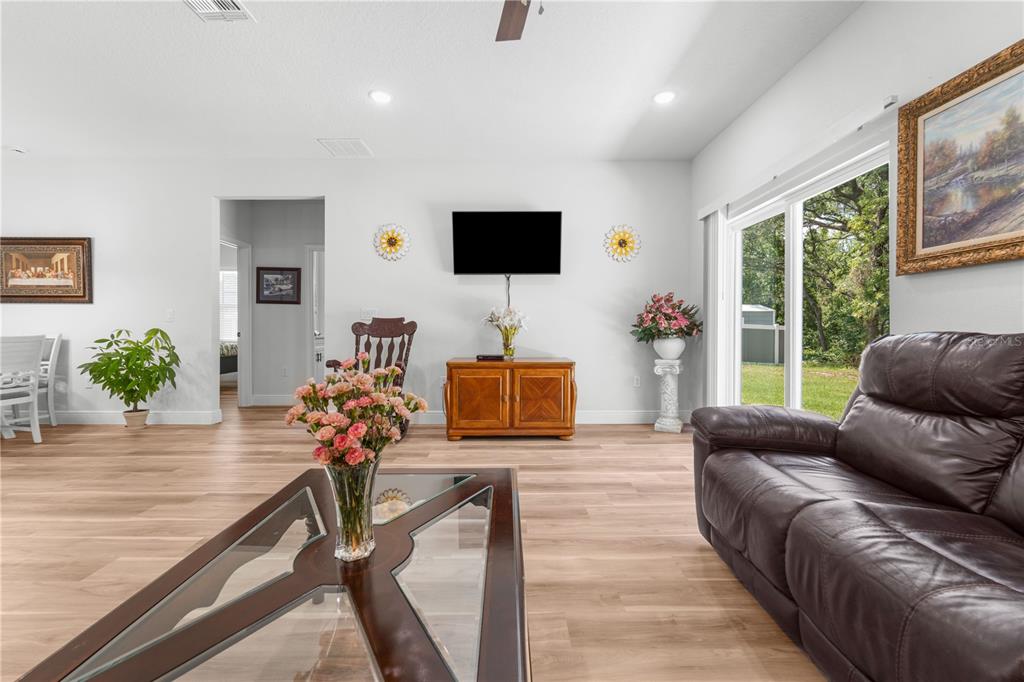 A living room features light wood flooring, a dark leather sofa, and a wall-mounted television — 768 MARION OAKS MANOR, OCALA, FL