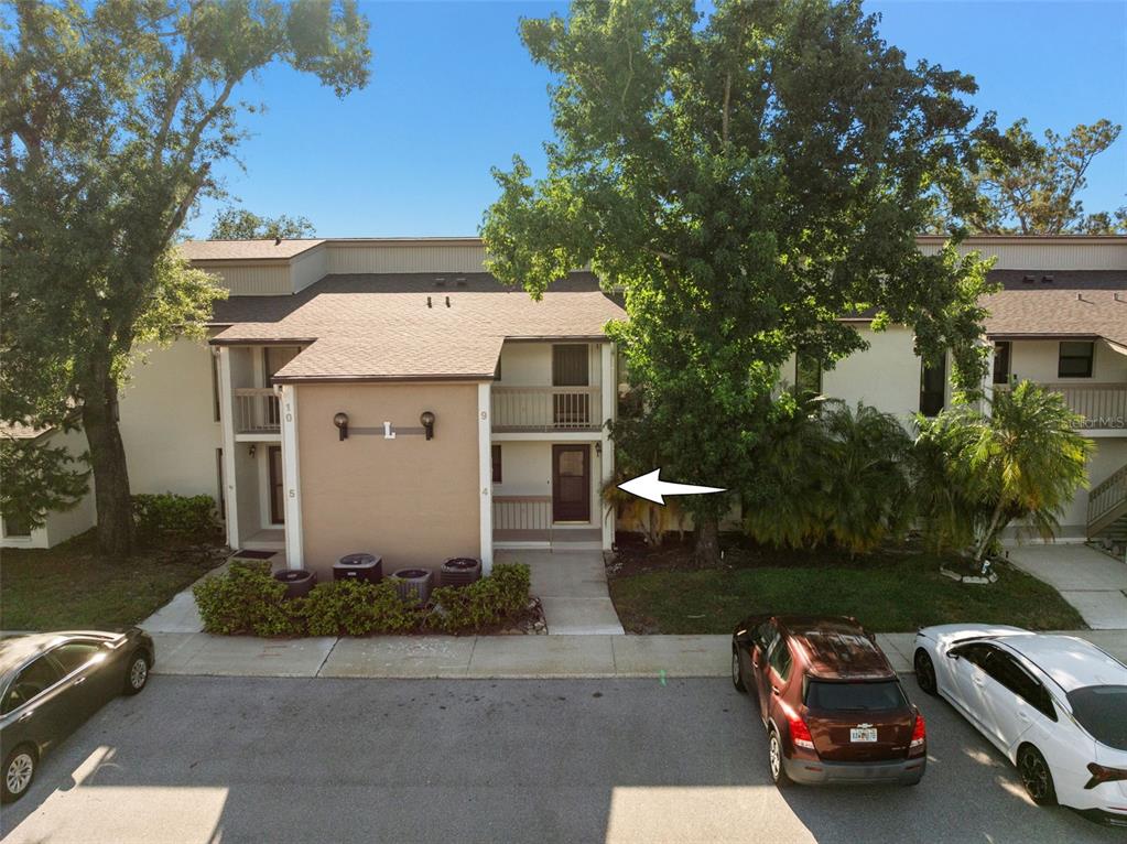 An exterior view of a two-story apartment building with a white arrow pointing to a door — 1200 TARPON WOODS BOULEVARD UNIT L4, PALM HARBOR, FL