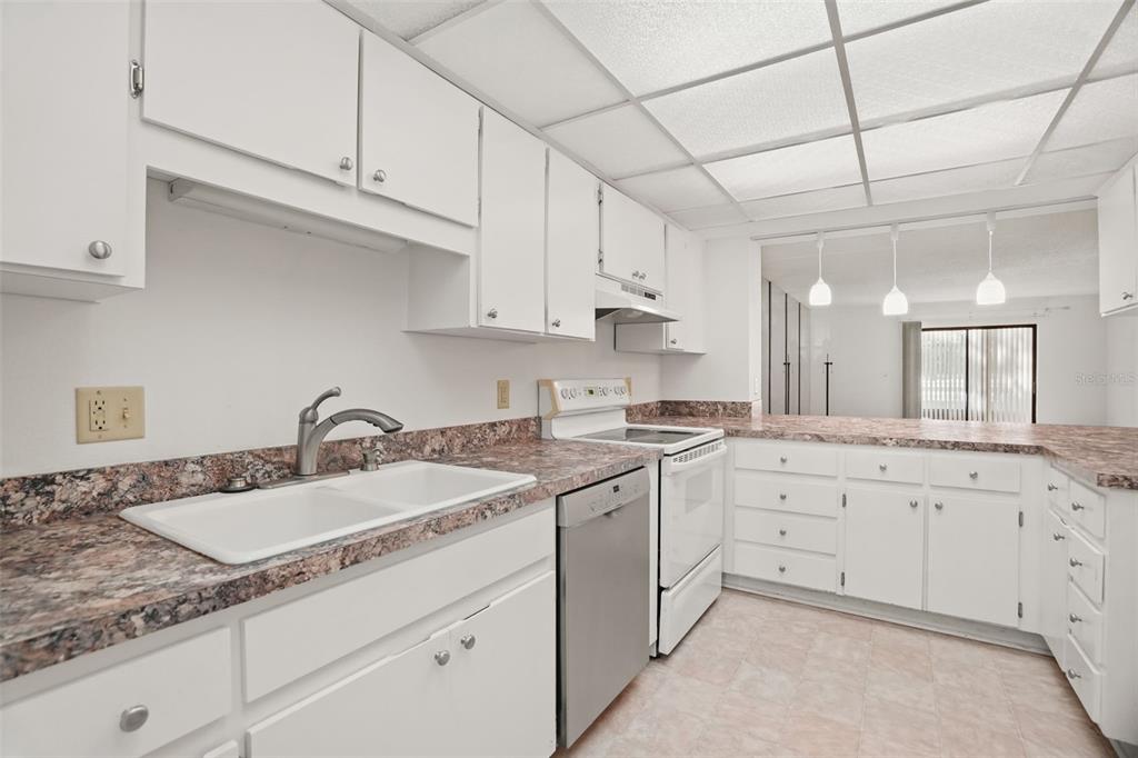 A kitchen with white cabinets, laminate countertops, and a stainless steel dishwasher and stove — 1200 TARPON WOODS BOULEVARD UNIT L4, PALM HARBOR, FL